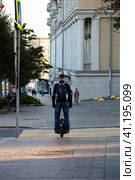 Man riding on unicycle through city street. Drive around city streets on electric monowheel. Редакционное фото, фотограф Константин Григорьев / Фотобанк Лори