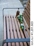 Empty beer bottles on bench in park. Urban alcoholism concept. Social issues of alcohol and immoral behaviour. Редакционное фото, фотограф Константин Григорьев / Фотобанк Лори
