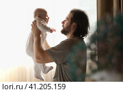 Young neo father is playing with his newborn baby in a nursery morning. Father's Day. Daddy holds in hands little Child and Plays with him. Concept of children, baby, parenthood, childhood, family. Стоковое фото, фотограф Марина Демидюк / Фотобанк Лори
