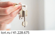 Close up of man holding key with house keychain in hand and walking in new apartment with cardboard boxes and ladder on background. Guy moving in new home. Buying or renting real estate concept. Стоковое видео, видеограф Igor Skripachev / Фотобанк Лори