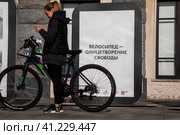 Посетитель Московского осеннего велофестиваля на фоне баннера с надписью "Велосипед - олицетворение свободы" на Речном вокзале в городе Москве, Россия (2023 год). Редакционное фото, фотограф Николай Винокуров / Фотобанк Лори