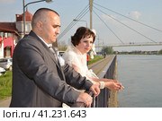 Sremska Mitrovica, Serbia October 10, 2019 a groom in a gray suit and a bride in a white dress are standing by the river. Стоковое фото, фотограф Юлия Петровская / Фотобанк Лори