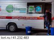 Женщина ждет своей очерди на вакцинацию у мобильного пункта бесплатной вакцинации от гриппа в специальном автомобиле скорой помощи в городе Москве, Россия (2023 год). Редакционное фото, фотограф Николай Винокуров / Фотобанк Лори