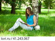 Happy woman leafing through a magazine while sitting in the summer park. Стоковое фото, фотограф Андрей Аркуша / Фотобанк Лори