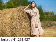 Beautiful girl in a beige dress posing on a background of haystacks in a cut field. Стоковое фото, фотограф Андрей Аркуша / Фотобанк Лори