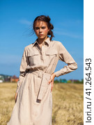 Young beautiful brunette model in a beige dress posing against the background of a mowed wheat field. Стоковое фото, фотограф Андрей Аркуша / Фотобанк Лори