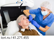 Cosmetologist making injections of botulotoxin in face of mature woman. Стоковое фото, фотограф Яков Филимонов / Фотобанк Лори