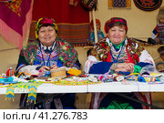 Две пожилые женщины в национальной одежде ханты и манси на фоне убранства, утвари, украшений (2018 год). Редакционное фото, фотограф Любовь Демус / Фотобанк Лори