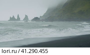 The black sand beach of Reynisfjara with waves hitting the shore on foggy rainy stormy day Vik, Icel. Стоковое видео, видеограф Igor Tichonow / Фотобанк Лори