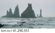 Sharp cliffs on black sand beach of Reynisfjara with waves hitting the shore on foggy rainy stormy d. Стоковое фото, фотограф Igor Tichonow / Фотобанк Лори