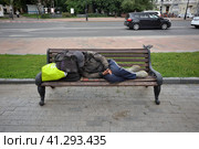 Moscow, Russia, July 11, 2023: Homeless dirty man sleeps on bench in city center. Редакционное фото, фотограф Алексей Антипов / Фотобанк Лори
