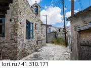 One of the central streets of Kato Lefkara. Very narrow and authentic stony street with wires posts. Cozy houses with colorful facades and red tiled roofs. Chapel with the bell in the middle. Одна из центральных улиц Като-Лефкара. Очень узкая и аутентичная каменистая улочка с проволочными столбами. Уютные домики с красочными фасадами и красными черепичными крышами. Часовня с колоколом посередине (2019 год). Стоковое фото, фотограф Дмитрий Березнев / Фотобанк Лори