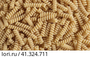 Gluten Free Cornmeal Pasta Wallpaper. Spiral Raw Macaroni from Corn and Rice flour rotating on Turntable. Close Up Top View. Uncooked Pasta Spinning. Full Frame. Food Background. Fusilli Bucati Corti. Стоковое видео, видеограф Марина Демидюк / Фотобанк Лори