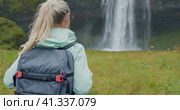 Closeup of female traveler back with backpack loking to Beautiful Seljalandsfoss waterfall Iceland. Стоковое видео, видеограф Igor Tichonow / Фотобанк Лори