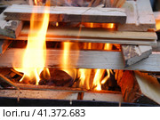 Огонь полыхает между дровами, сложенными друг на друга. Несколько сосновых и березовых поленьев сложены в квадратную башню, в центре которой ярко горят дрова и щепа. Стоковое фото, фотограф Andrew_Swarga / Фотобанк Лори
