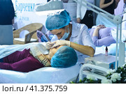 Cosmetologists perform a procedure to rejuvenate facial skin cosmetics Aravia at the festival of beauty Nevskie Berega in St. Petersburg 2012. Редакционное фото, фотограф Анна Кривицкая / Фотобанк Лори