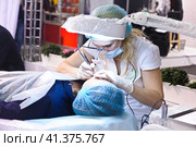 Cosmetologists perform a procedure to rejuvenate facial skin cosmetics Aravia at the festival of beauty Nevskie Berega in St. Petersburg 2012. Редакционное фото, фотограф Анна Кривицкая / Фотобанк Лори