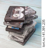 A careless stack of audio cassettes stands against a blue wooden background. Vertical orientation. Стоковое фото, фотограф Воловодов Владимир / Фотобанк Лори