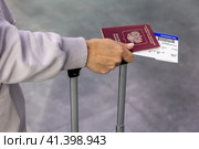 Россия. Санкт-Петербург. Пассажирка держит российский паспорт и посадочный талон. Russia. Saint-Petersburg. The passenger holds a Russian passport and boarding pass. (2023 год). Стоковое фото, фотограф Алексей Смышляев / Фотобанк Лори