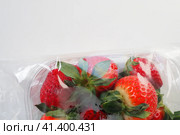 Ripe strawberries in a plastic package on a white background. Delicious fresh berries in a container for sale to customers. Keeping food fresh. Healthy food, vitamins and microelements. Стоковое фото, фотограф Юлия Петровская / Фотобанк Лори