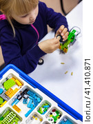 Kid girl 5 year old inventing robotic toys in programming class, construct robot. Child using constructor blocks and PC, technology homework. Learning robotics basics concept. Copy ad text space. Стоковое фото, фотограф Aleksandr Golubev / Фотобанк Лори