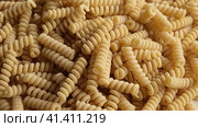 Gluten Free Cornmeal Pasta Wallpaper. Spiral Raw Macaroni from Corn and Rice flour rotating on Turntable. Close Up Top View. Uncooked Pasta Spinning. Full Frame. Food Background. Fusilli Bucati Corti. Стоковое видео, видеограф Марина Демидюк / Фотобанк Лори