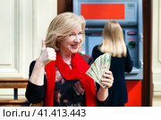 Mature blonde woman counting money near ATM. Стоковое фото, фотограф Андрей Аркуша / Фотобанк Лори