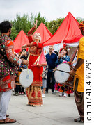 Indian drummer playing traditional dhol instrument and russian woman dancing in the street. Fest day of india in Moscow (2023 год). Редакционное фото, фотограф Константин Григорьев / Фотобанк Лори