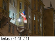 American Stars and Stripes flag on the building in the autumn night. Embassy of the United States of America, Moscow. Electric light (2022 год). Стоковое фото, фотограф YuryKara / Фотобанк Лори