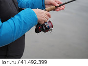Нижний Новгород, Россия, река Ока, 20.10.2023. Рыбная ловля. Женщина-рыбак с удочкой на берегу реки осенью. Спиннинговое удилище с катушкой, бечевкой и приманкой. Редакционное фото, фотограф Egor Sarantstv / Фотобанк Лори