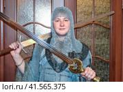 A man dressed up in a knight's hauberk at home in his room. Knight's sword in the hands of a man. Стоковое фото, фотограф Леонид Еремейчук / Фотобанк Лори