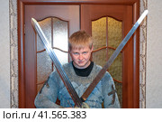 A man dressed up in a knight's hauberk at home in his room. Knight's sword in the hands of a man. Стоковое фото, фотограф Леонид Еремейчук / Фотобанк Лори