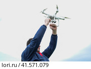 A man with a quadrocopter in his arms raised to the sky. A white drone is being prepared for the flight. Стоковое фото, фотограф Леонид Еремейчук / Фотобанк Лори