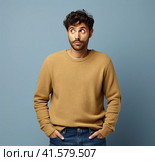 A young man stands against a gray wall with his hands in his pockets and looks thoughtfully to the side. The concept of puzzlement. Generated by AI. Стоковое AI-изображение, AI-художник Ярославский Максим / Фотобанк Лори