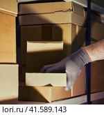 A man in gloves steals goods from a box in a warehouse. Problems with theft and security in the office. Стоковое фото, фотограф Андрей Журавлев / Фотобанк Лори