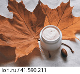 White jar with oily cream for cold weather against a background of red maple leaves. Стоковое фото, фотограф burnet / Фотобанк Лори