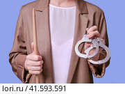 Woman teacher holding handcuffs in her hands on a blue background, close-up. Стоковое фото, фотограф Андрей Журавлев / Фотобанк Лори