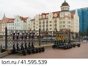 Kaliningrad, Russia - June 20, 2022: Cityscape in day. Bank of Pregol River and the Fishing village. Famous touristic location. New buildings. Yubileyny bridge. Parking of the renting motor scooters. Редакционное фото, фотограф YuryKara / Фотобанк Лори