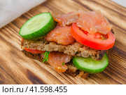 Red fish sandwich with wholegrain bread and vegetables laying on a wooden board. Стоковое фото, фотограф Воловодов Владимир / Фотобанк Лори