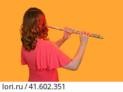 Woman musician with a flute on a studio yellow background. Flutist with a large concert transverse flute, close up. Стоковое фото, фотограф Андрей Журавлев / Фотобанк Лори