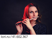 Portrait of a woman musician with a piccolo flute on a studio black background. Flutist with a small flute in her hands. Стоковое фото, фотограф Андрей Журавлев / Фотобанк Лори