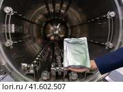 Пакет с готовым продуктом на фоне рабочего пространства промышленного автоклава для стерилизации консервов и иной пищевой продукции (2023 год). Редакционное фото, фотограф Сайганов Александр / Фотобанк Лори
