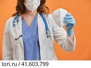 A nurse holds a medical mask n95 ffp2 in her hand. The concept of protecting doctors during the coronavirus epidemic. Стоковое фото, фотограф Андрей Журавлев / Фотобанк Лори