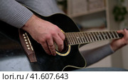 Playing the guitar. Strumming black acoustic guitar. Musician plays music. Man fingers holding mediator. Male hand playing guitar neck in dark room. Unrecognizable person rehearsing, fretboard closeup. Стоковое видео, видеограф Марина Демидюк / Фотобанк Лори