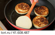 Cottage cheese fritters are fried in a pan and turned over with a spatula close up. Homemade food. Preparing healthy tasty breakfast cheese cakes. Russian, Ukrainian, Belorussian cuisine. Стоковое видео, видеограф Мария Зубарева / Фотобанк Лори