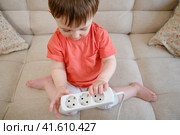 The baby needs to be kept away from electrical cords at home to prevent any danger of electric shock or injury. Kid aged about two years (one year ten months) Стоковое фото, фотограф Андрей Журавлев / Фотобанк Лори