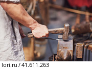 A blacksmith in a forge forges metal. Blacksmithing in retro style outdoors. Стоковое фото, фотограф Андрей Журавлев / Фотобанк Лори