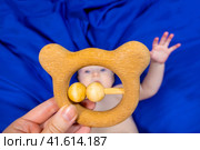 a baby on a blue background with a wooden rattle. Стоковое фото, фотограф Anastasia Kayander / Фотобанк Лори