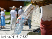 Женская рука держит бутылку и наливает воду из источника жарким летним днем. Стоковое фото, фотограф Pukhov K / Фотобанк Лори