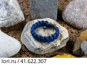 Braided paracord bracelet on the background of stones. Handmade, creative design. Стоковое фото, фотограф Артем Лукин / Фотобанк Лори